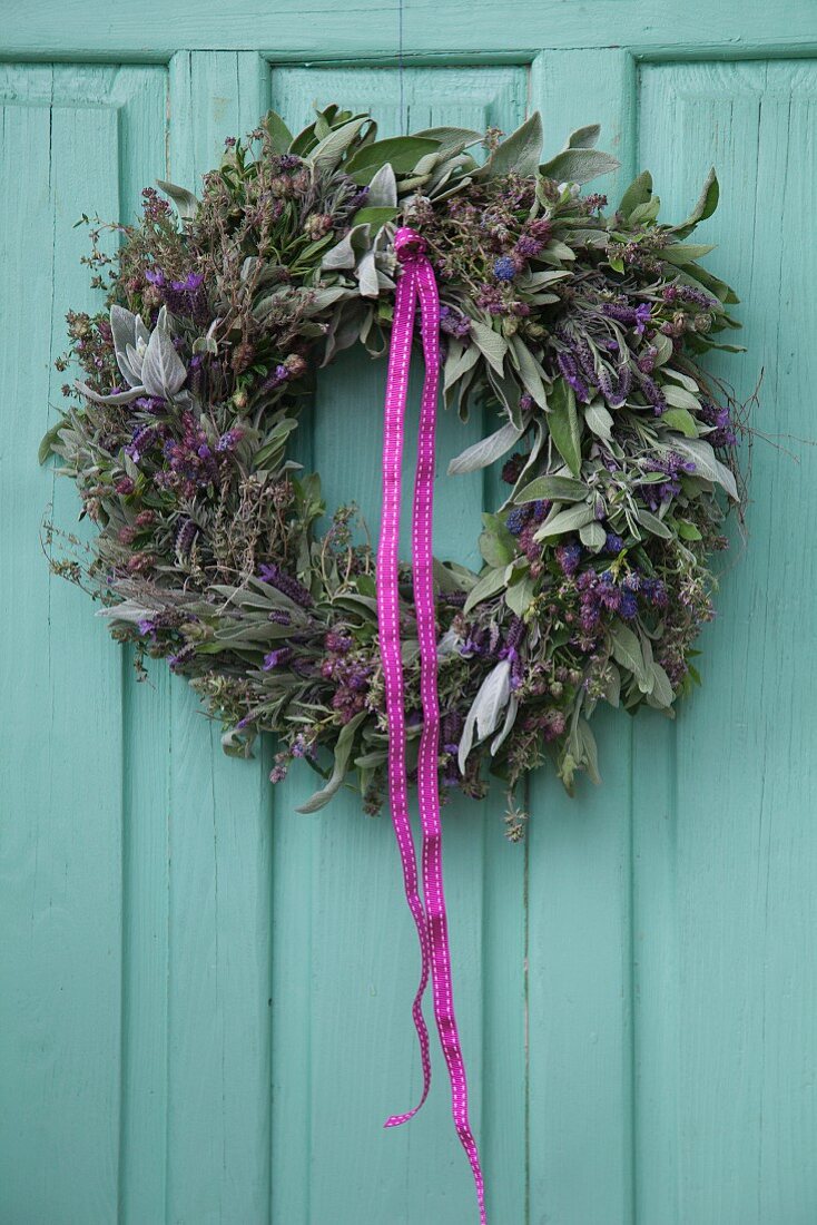 Kräuterkranz aus Lavendel und Salbei an türkisfarbener Holztür aufgehängt
