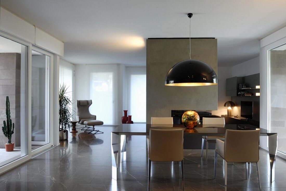 Spherical gold artwork on designer table with armchairs and view into minimalist lounge area