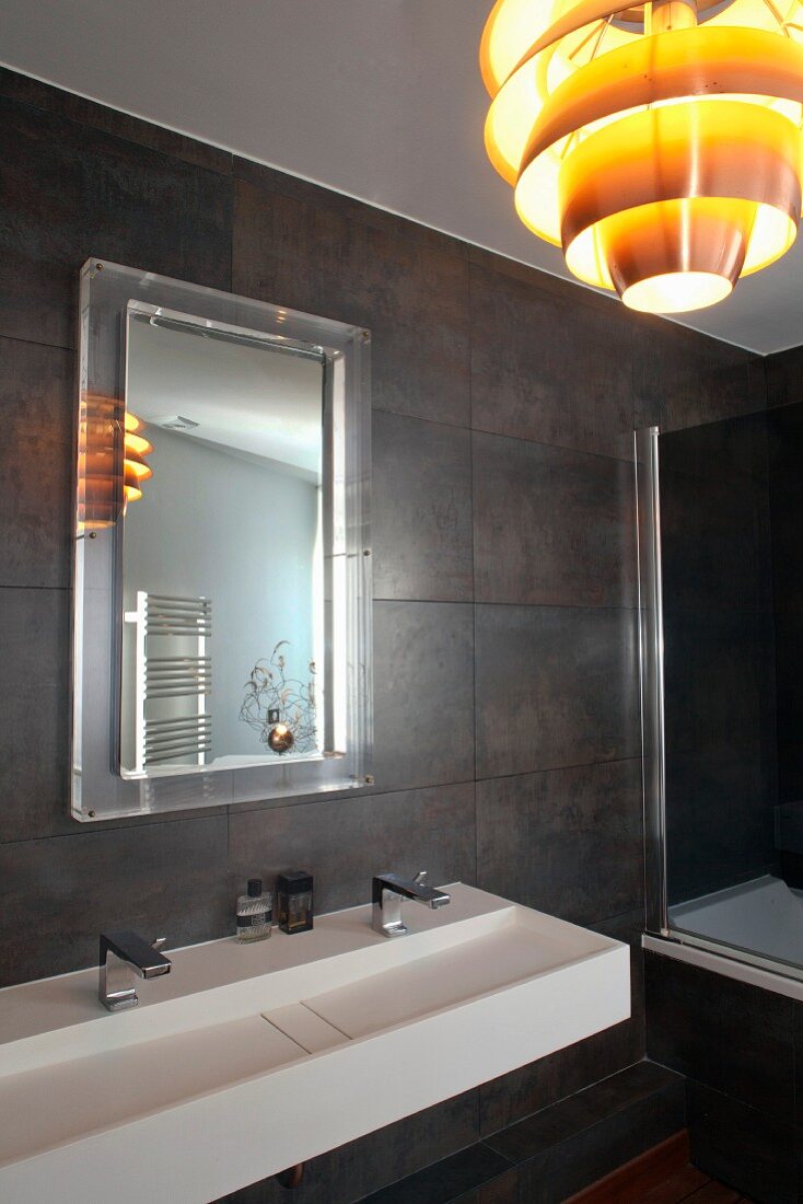 Modernes Bad mit dunklen Wandfliesen, weißem Designer-Doppelwaschbecken und Retro- Pendelleuchte