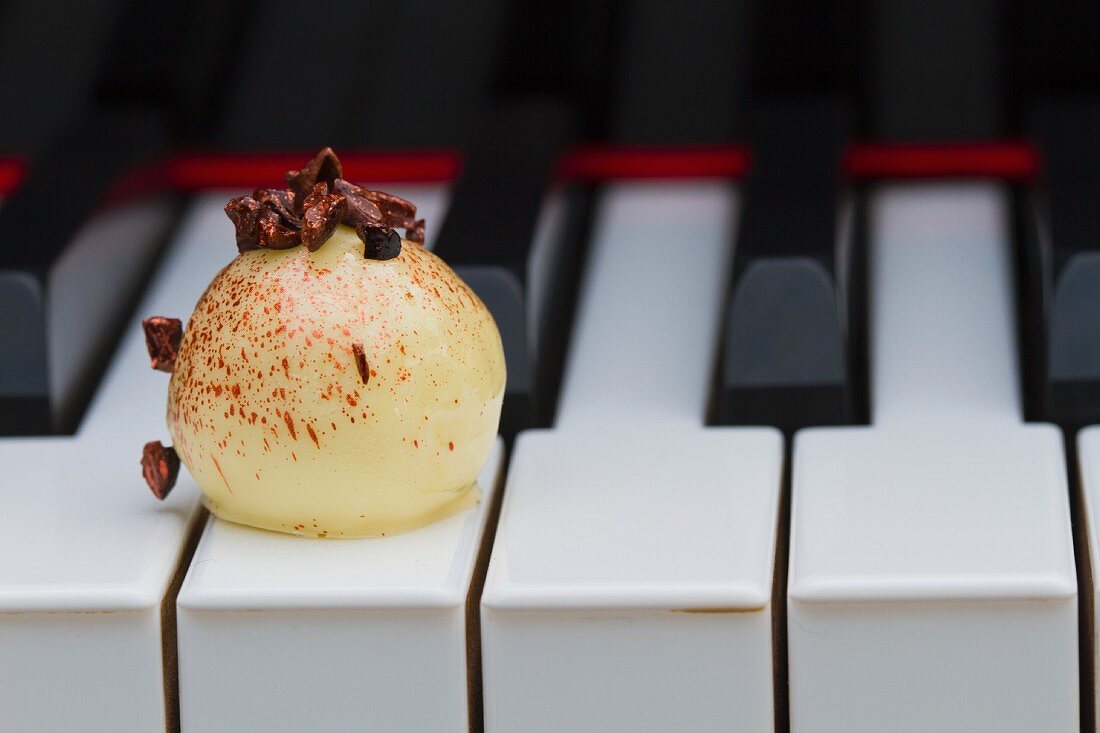 A white praline on the keys of a piano