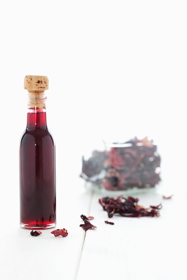 A bottle of hibiscus syrup and dried hibiscus flowers