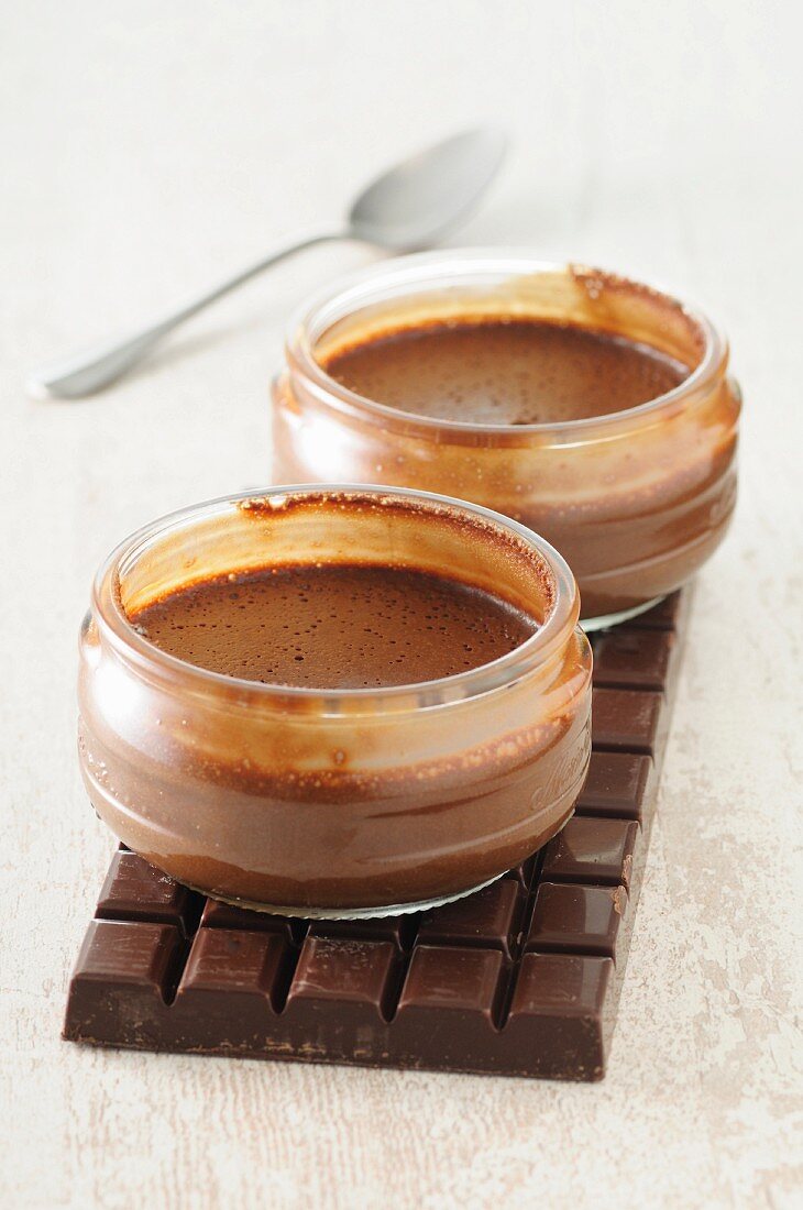 Two bowls of chocolate mousse on a bar of chocolate