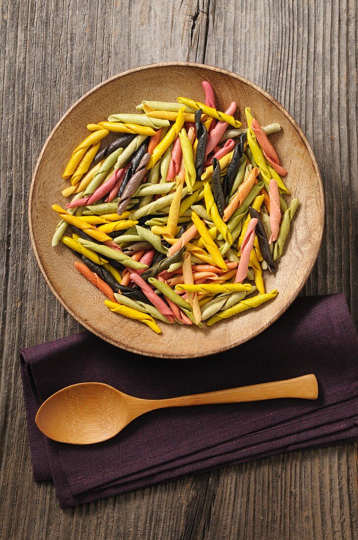 Colourful pasta in a wooden bowl (seen from above)