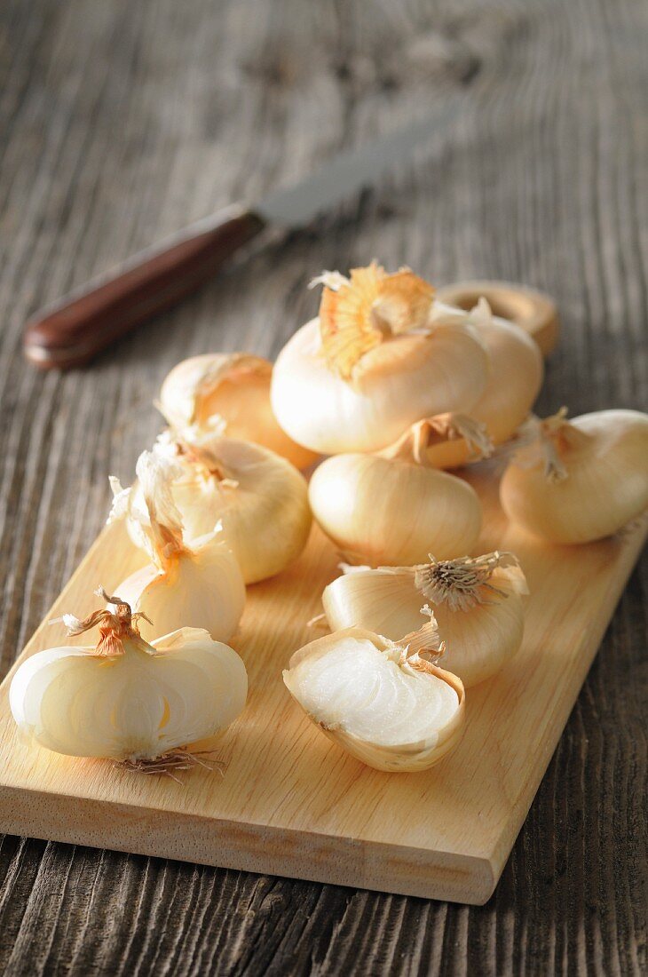 White onions, partially sliced, on a chopping board