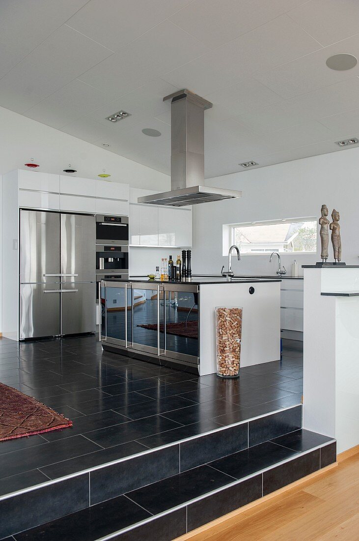 Stainless steel extractor hood above island counter in open-plan designer kitchen