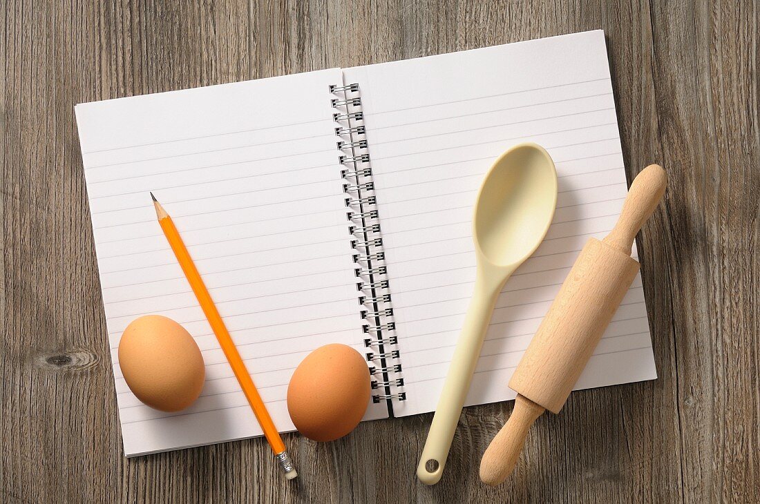 Notizbuch, Küchenutensilien und Eier
