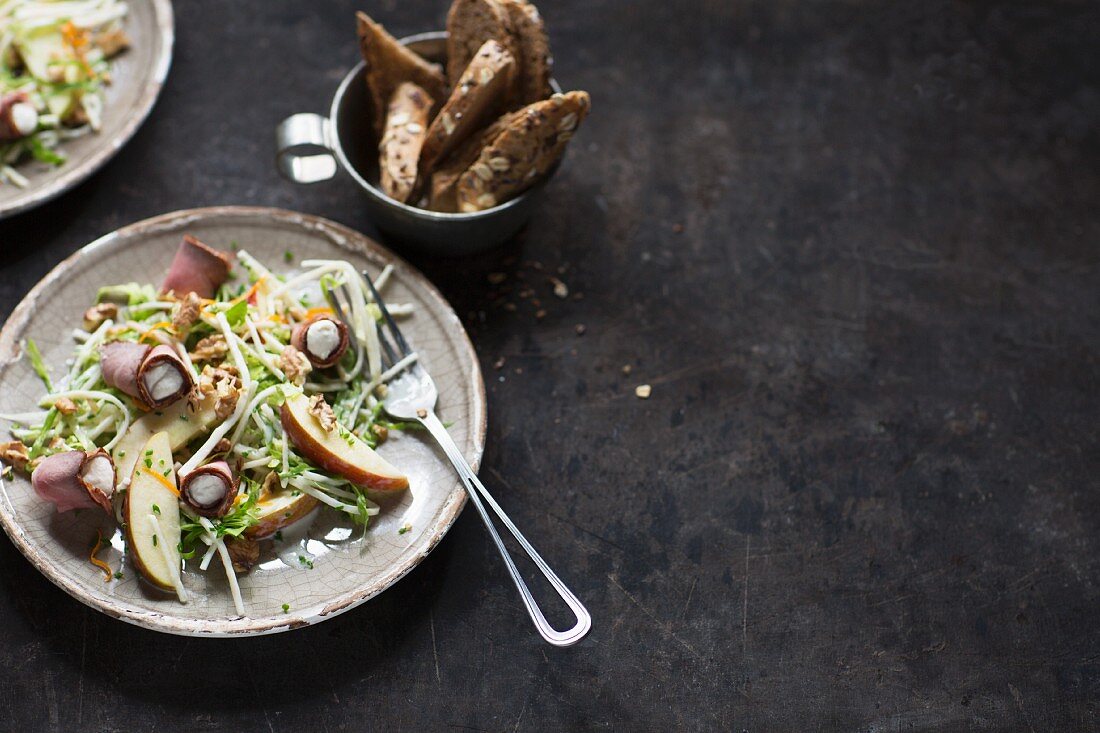 A healthy salad with ham rolls and apple