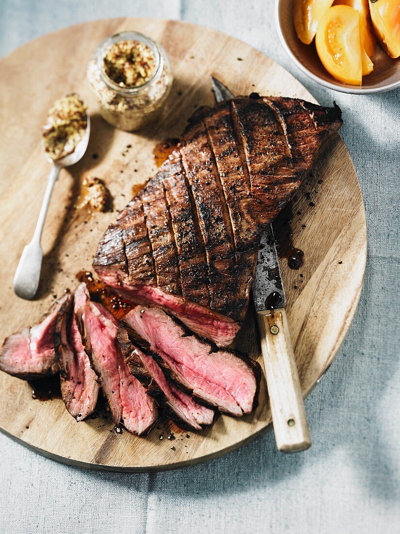 Striploin Steak auf Holzbrett, teilweise in Scheiben geschnitten