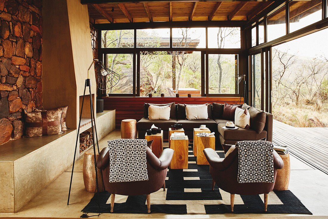 Blankets on backrests of leather chairs and solid wooden side tables in Colonial-style living room