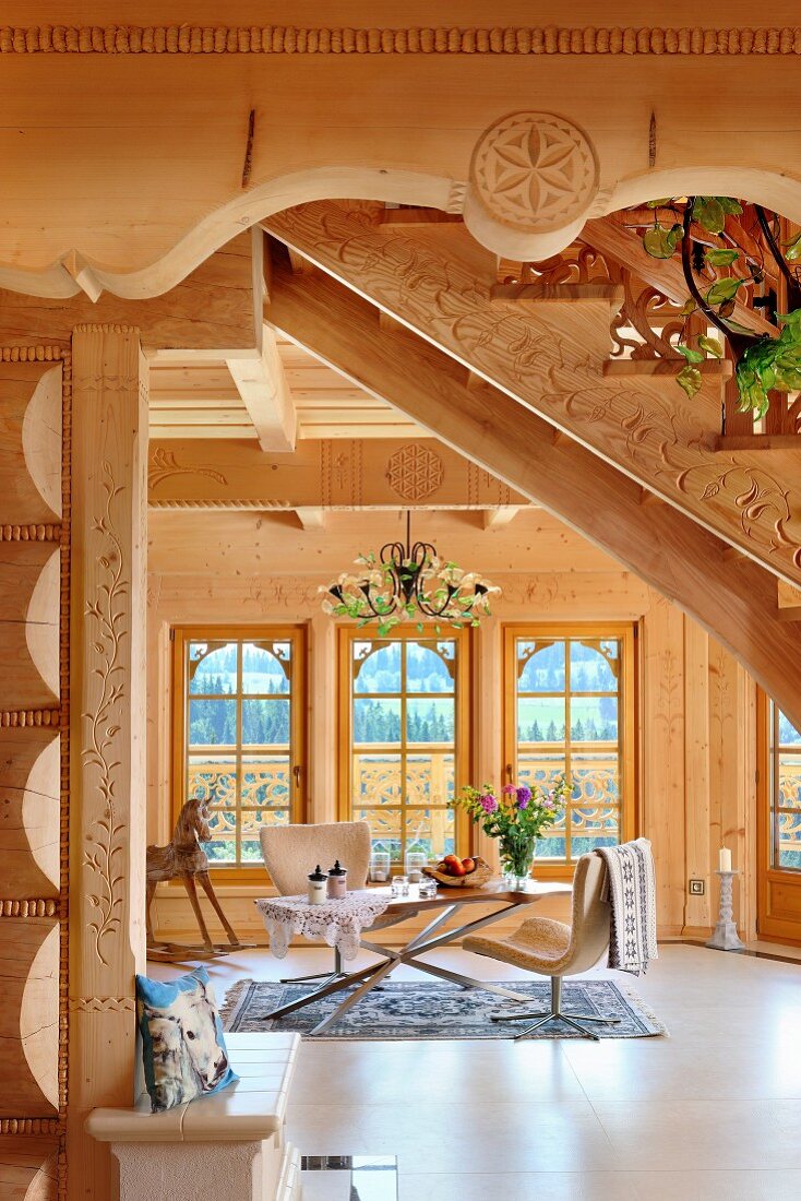 View under staircase of modern chairs around table in living area of solid-wood house
