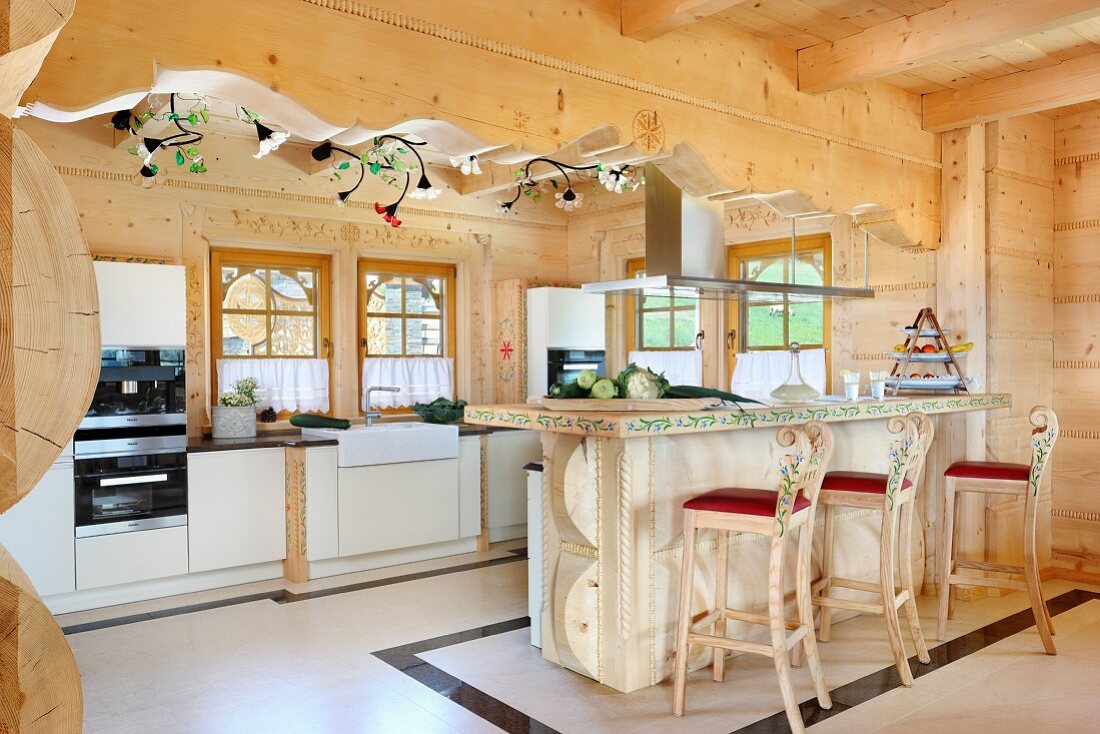 Esstheke und Barhocker aus geschnitztem Holz, teilweise bemalt in offener, moderner Küche in Massivholzhaus