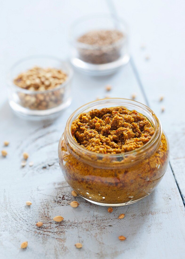 A jar of homemade madras curry paste with coriander seeds