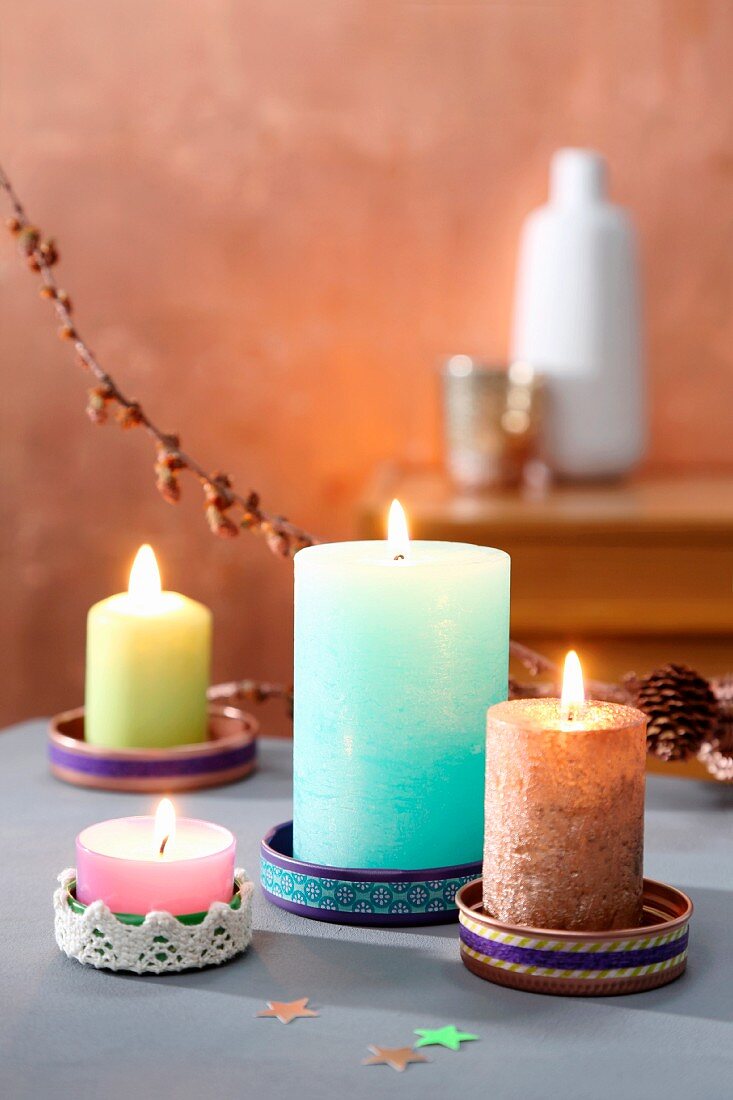 Colourful candles in saucers made from tin lids