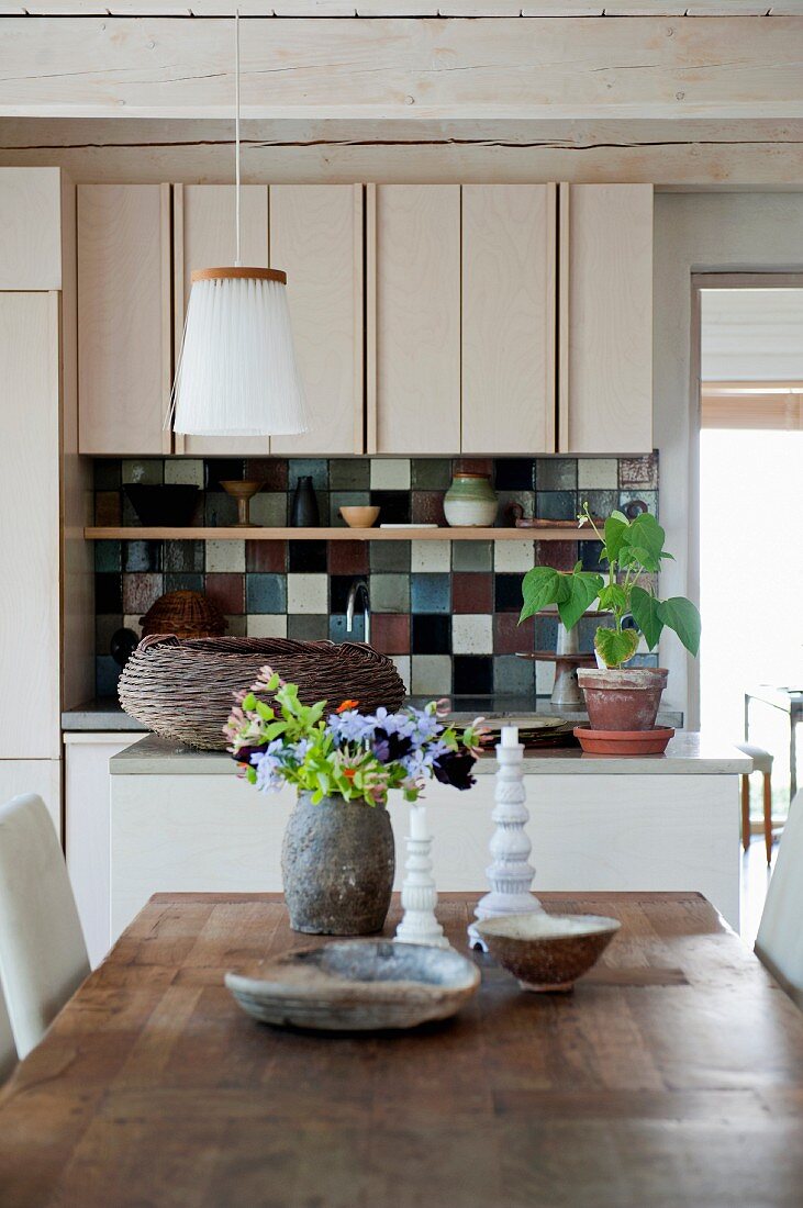 Blick von Holztisch auf Küchenzeile mit bunten Keramikwandfliesen