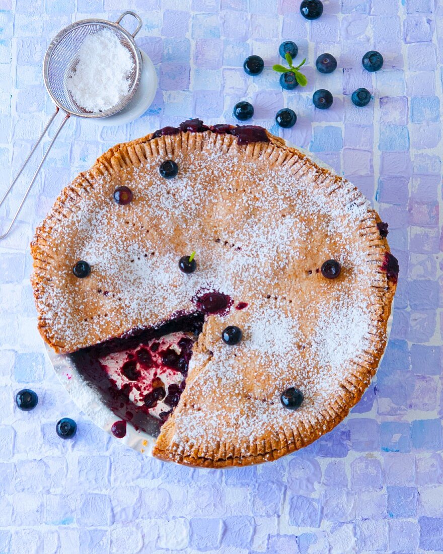 Blueberry pie with icing sugar, sliced