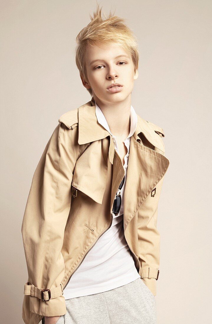 A young woman with short hair wearing a beige trench coat