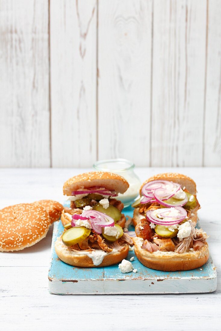 Burgers with pork, gherkins, horseradish cream sauce, red onions and feta cheese