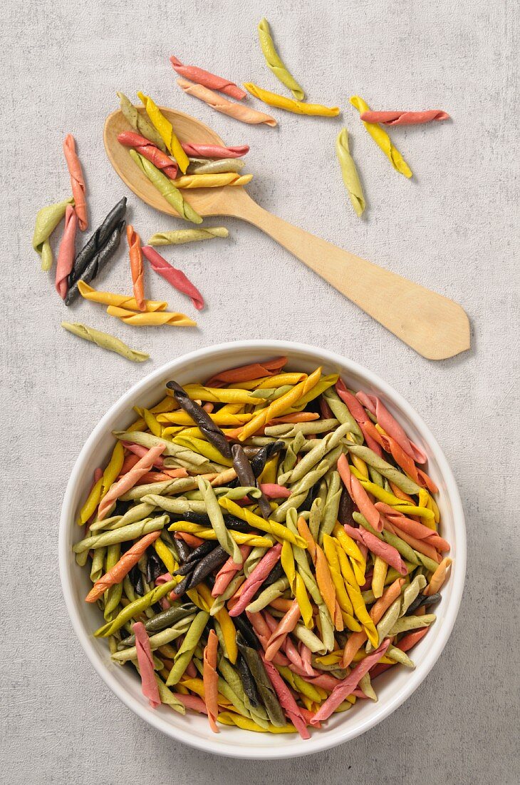 Colourful pasta in a bowl and next to it (seen from above)