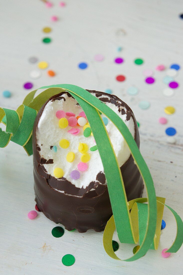 A half eaten chocolate candy with sugar confetti and streamers