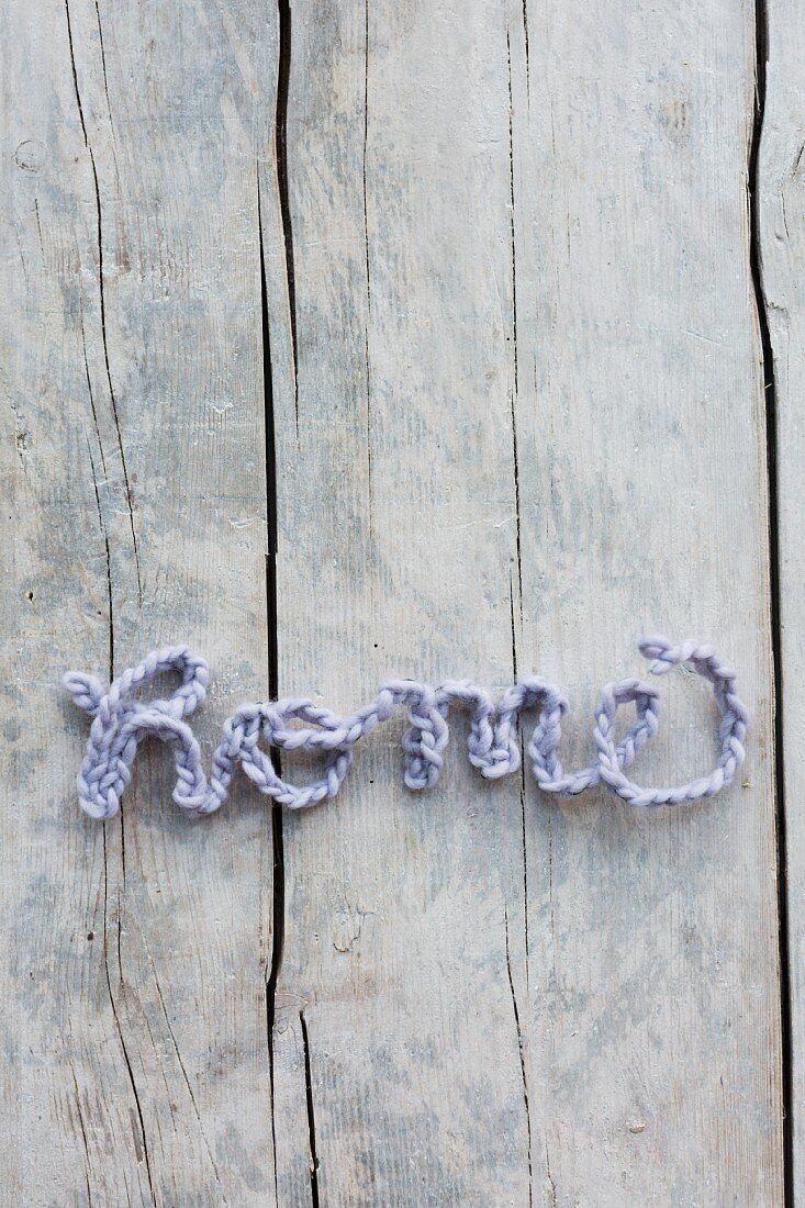 Crocheted cord arranged to spell 'Home' on vintage wooden surface