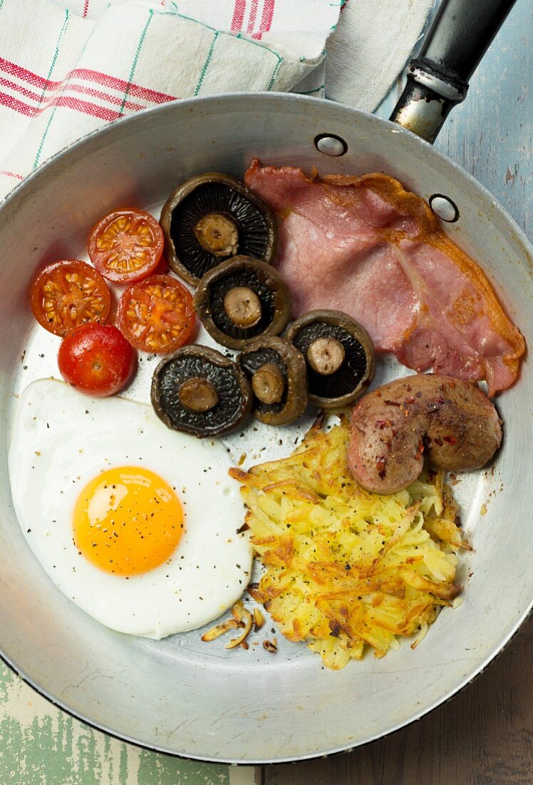 Englisches Frühstück mit Spiegelei, Bacon, Rösti, Pilzen und Tomaten