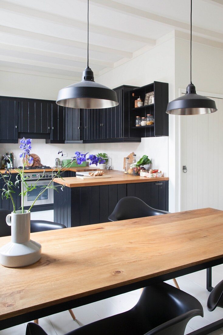 View of black country-house kitchen across wooden table