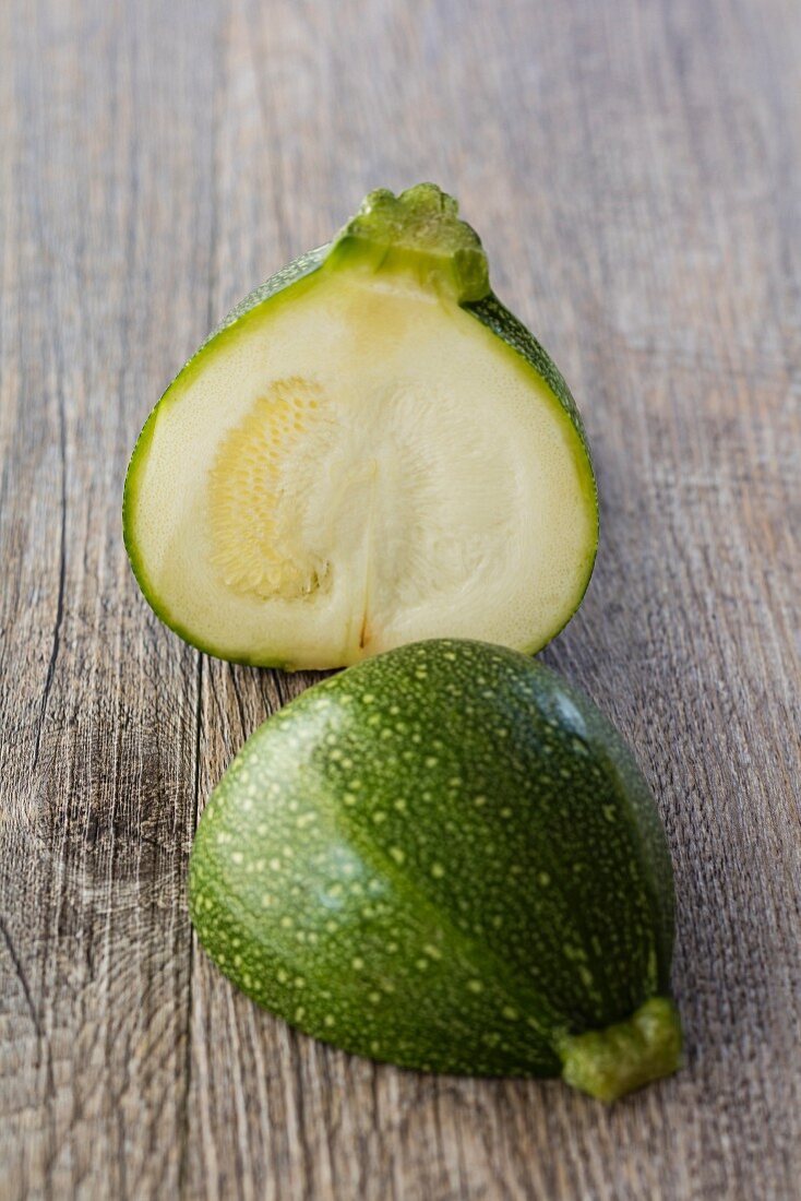 A round, green Eight Ball courgette, halved