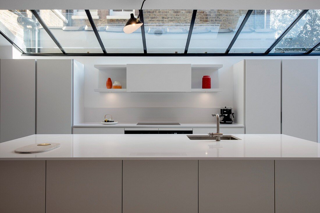 weiße Designerküche mit Küchentheke unter Glasdach