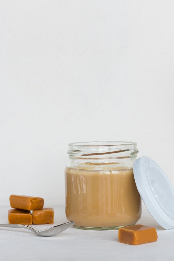 Cooked caramel pudding in a jar with a lid and a spoon