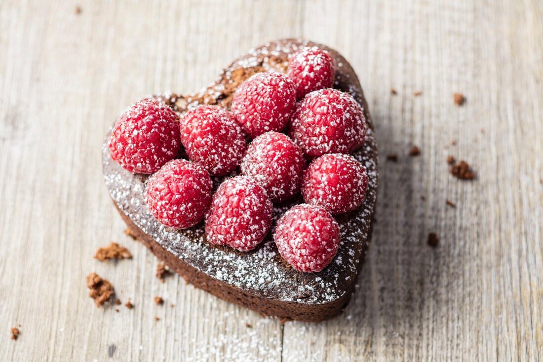 A mini heart-shaped chocolate cake with raspberries (gluten free)