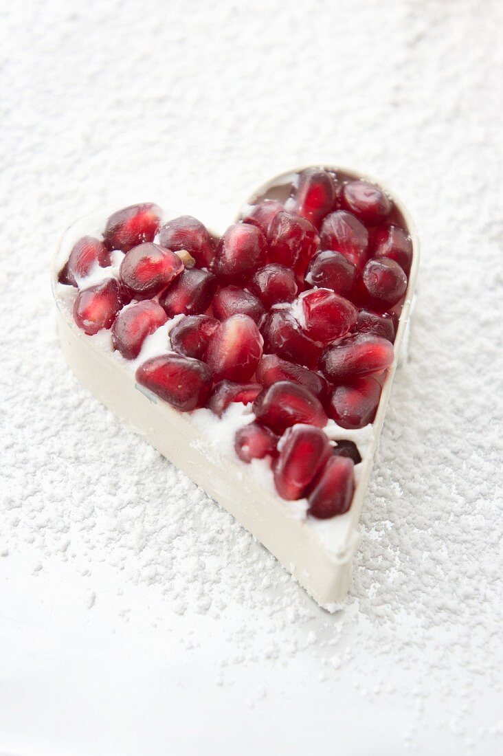 A white chocolate heart with pomegranate seeds in a mold
