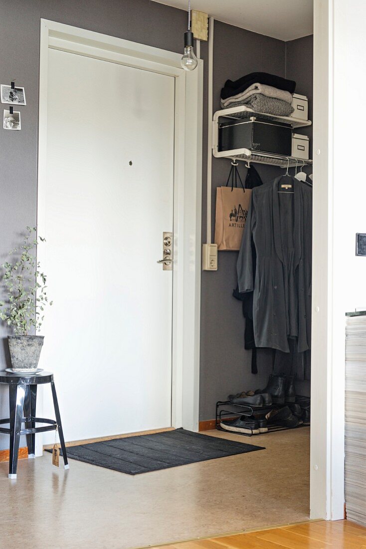 Blick in grau getönten Flur auf weiße Tür und reduzierte Garderobe