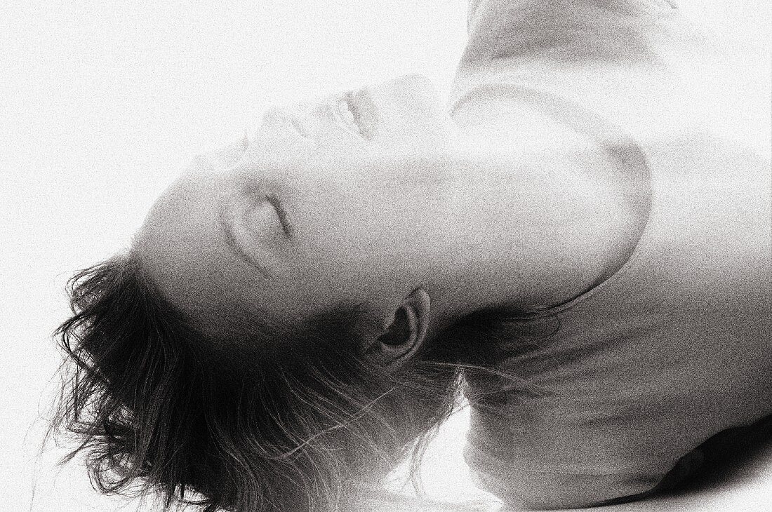 A portrait of a young woman lying down with her eyes closed (black-and-white shot)