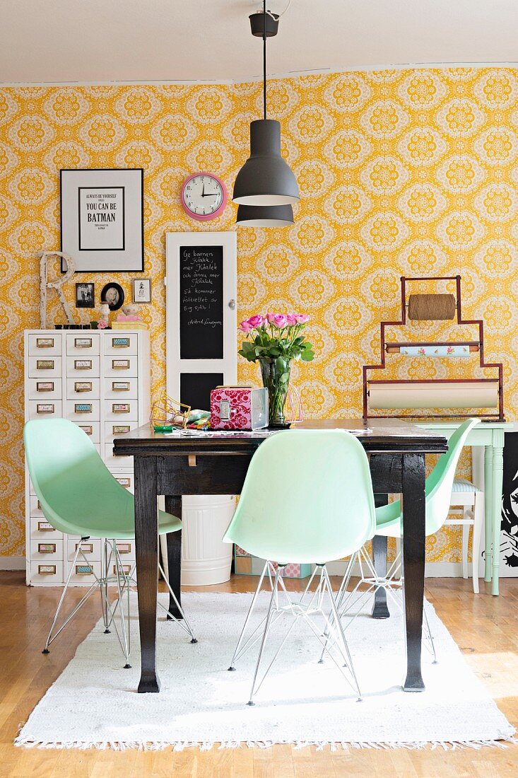 Pastellgrüne Schalenstühle um dunkelbrauen Holztisch in Esszimmer mit gelb-weiss gemusterter Tapete