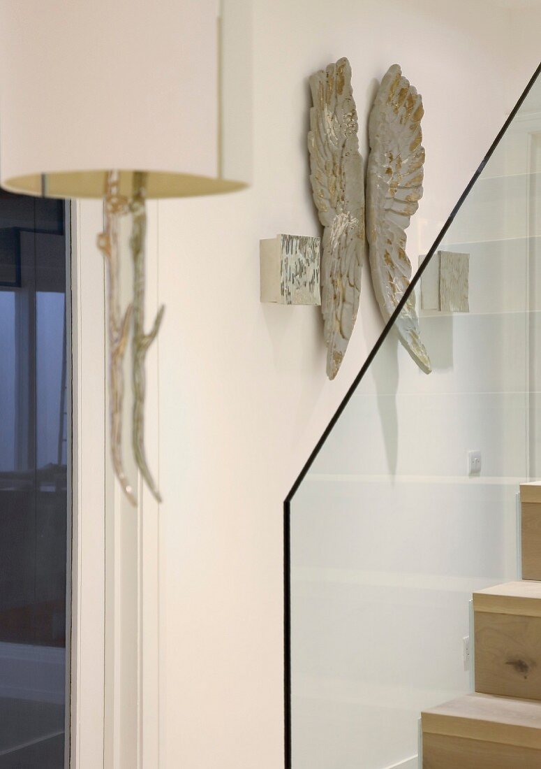 Staircase with glass balustrade, artwork on wall and sconce lamps