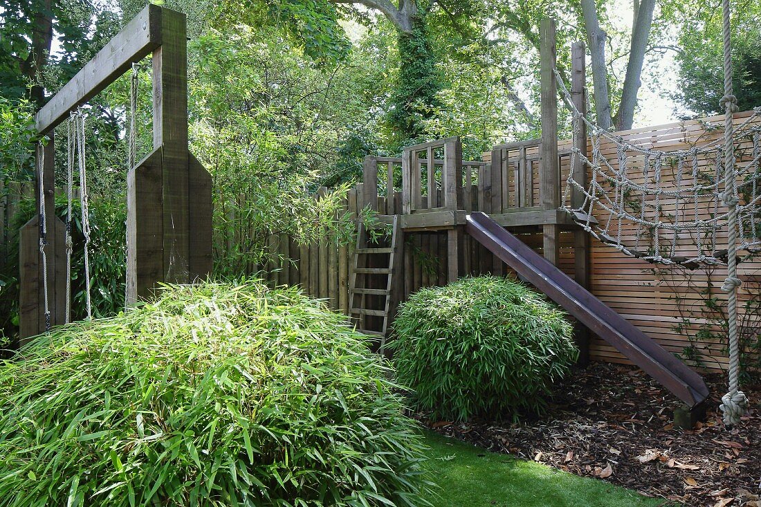 Spielplatz mit Holz-Klettergerüst in sommerlichem Garten