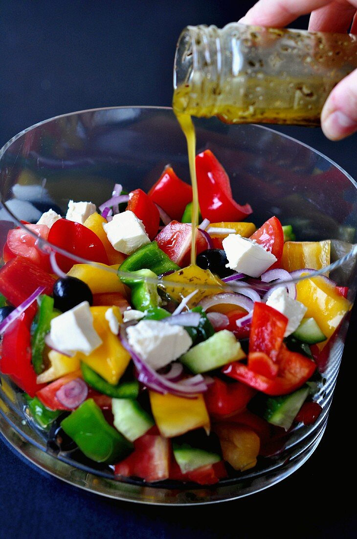 Dressing being poured over a vegetable salad