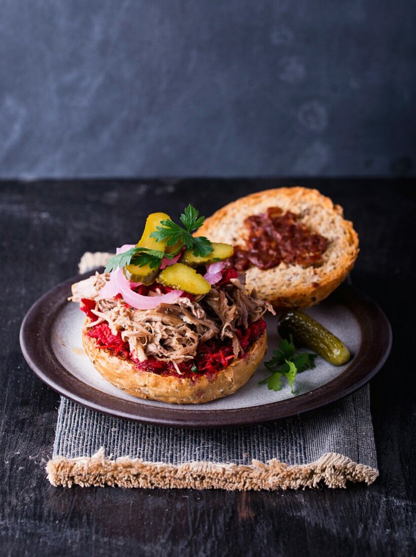 A pulled pork burger with gherkins and onions