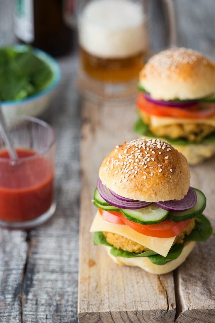 Hausgemachte vegane Quinoa-Burger mit Spinat, Tomaten, Gurken, Zwiebeln und Käseersatz