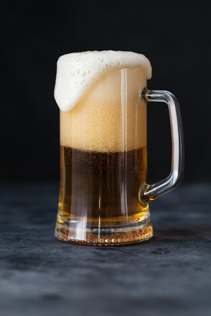 A glass of beer with overflowing foam