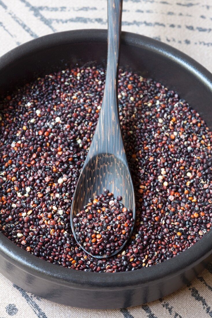 Black quinoa in a bowl with a wooden spoon