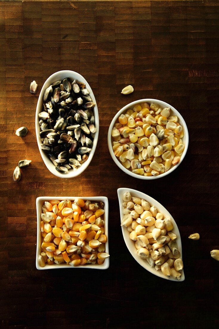 Various types of corn kernels in bowls (seen from above)