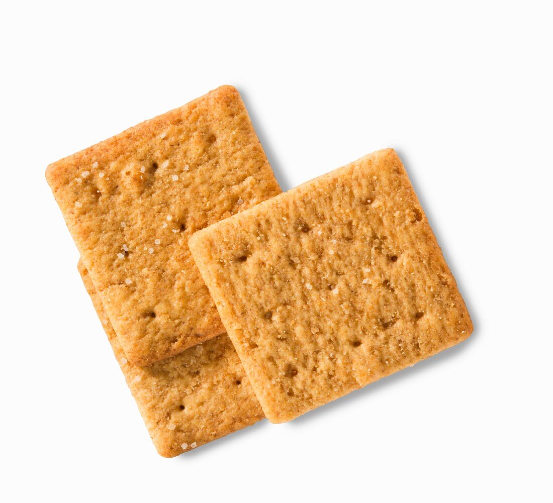 Three wheat crackers on a white surface (close-up)
