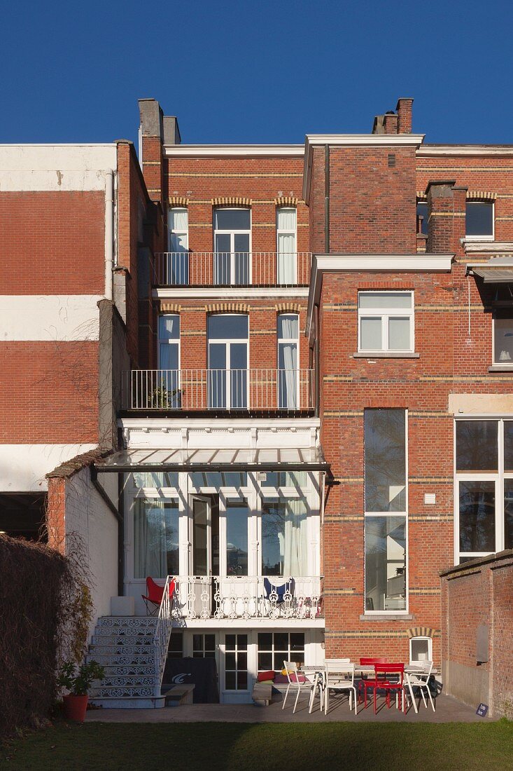 Four-storey brick town house with balcony outside raised ground floor and terrace in garden