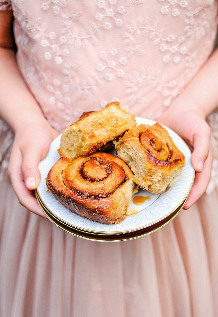 A little girl holding a plate of cinnamon buns