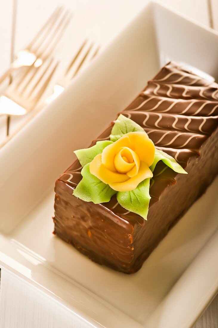 A slice of chocolate cake with a marzipan rose