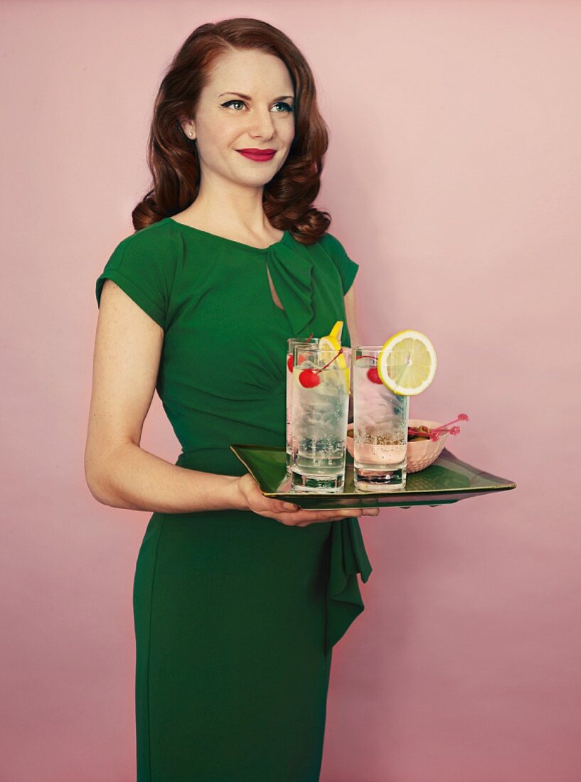 A woman holding a tray of Tom Collins cocktails