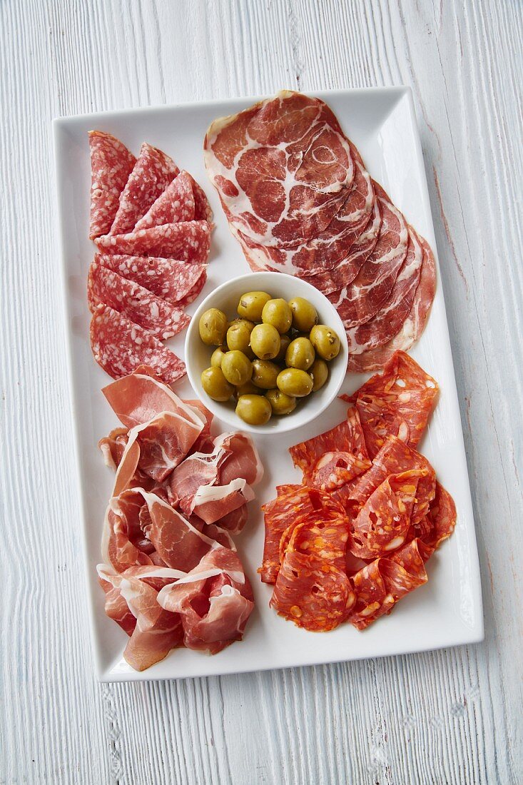 An Italian antipasti platter with ham, salami and olives