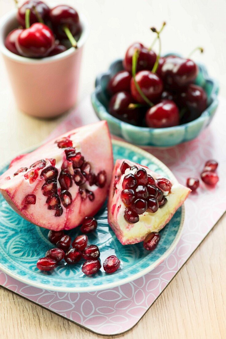 A sliced pomegranate and cherries