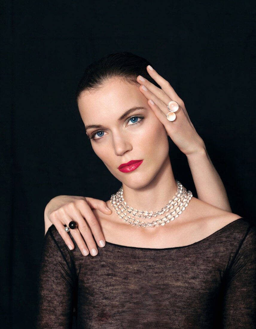 Young woman wearing necklace of crystal beads; hands wearing rings of crystal beads